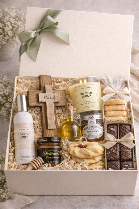 Gift box with various items including a candle, cross, and cookies on a neutral background