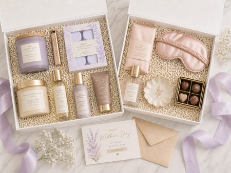 Gifting set with skincare products, a candle, and a sleep mask on a marble surface.