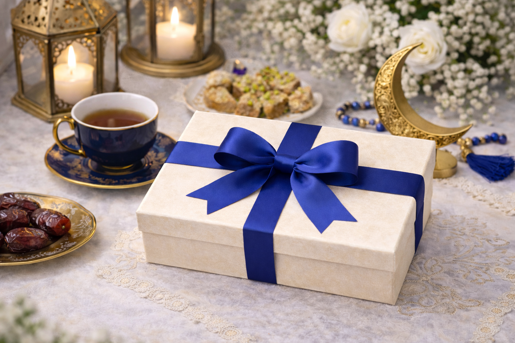 Gift box with blue ribbon on a table with tea, dates, and decorative items.