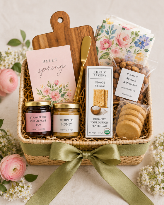 Gift basket with snacks, bread, and a cutting board on a light background