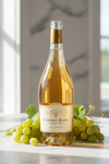 Bottle of Chateau Blanc Grand Cru wine with grapes on a marble surface
